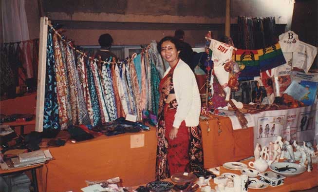 Mithu Dam, MKS founder, at an early craft fair stall — textiles, scarves and small leather goods on display.